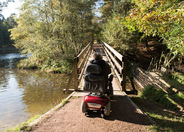 Image of a man driving over a bridge in a electric wheelchair